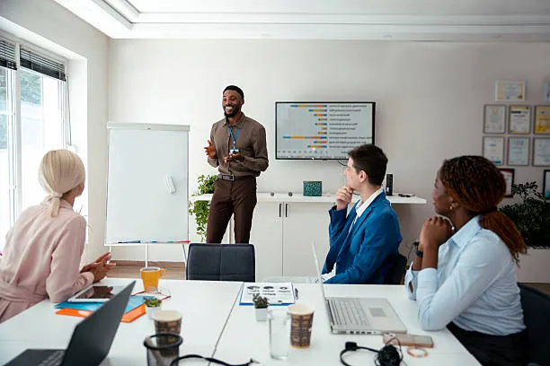 Persona en oficina durante junta de trabajo explicando cómo estructurar campañas de marketing para negocios.