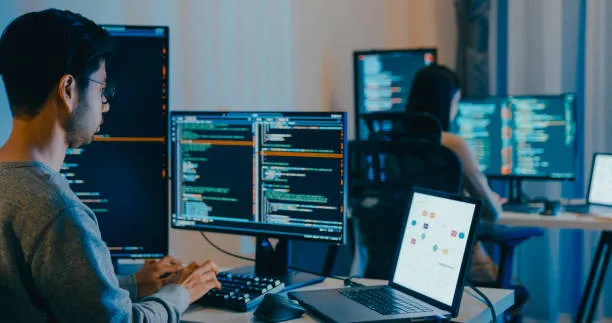 Monitores interactivos en oficina con códigos HTML usados en la construcción de una página web profesional efectiva.