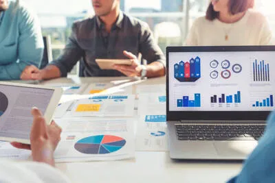 Cómo atraer clientes a un negocio nuevo con una persona revisando información digital en una computadora para planificar campañas y mejorar la presencia de una empresa.